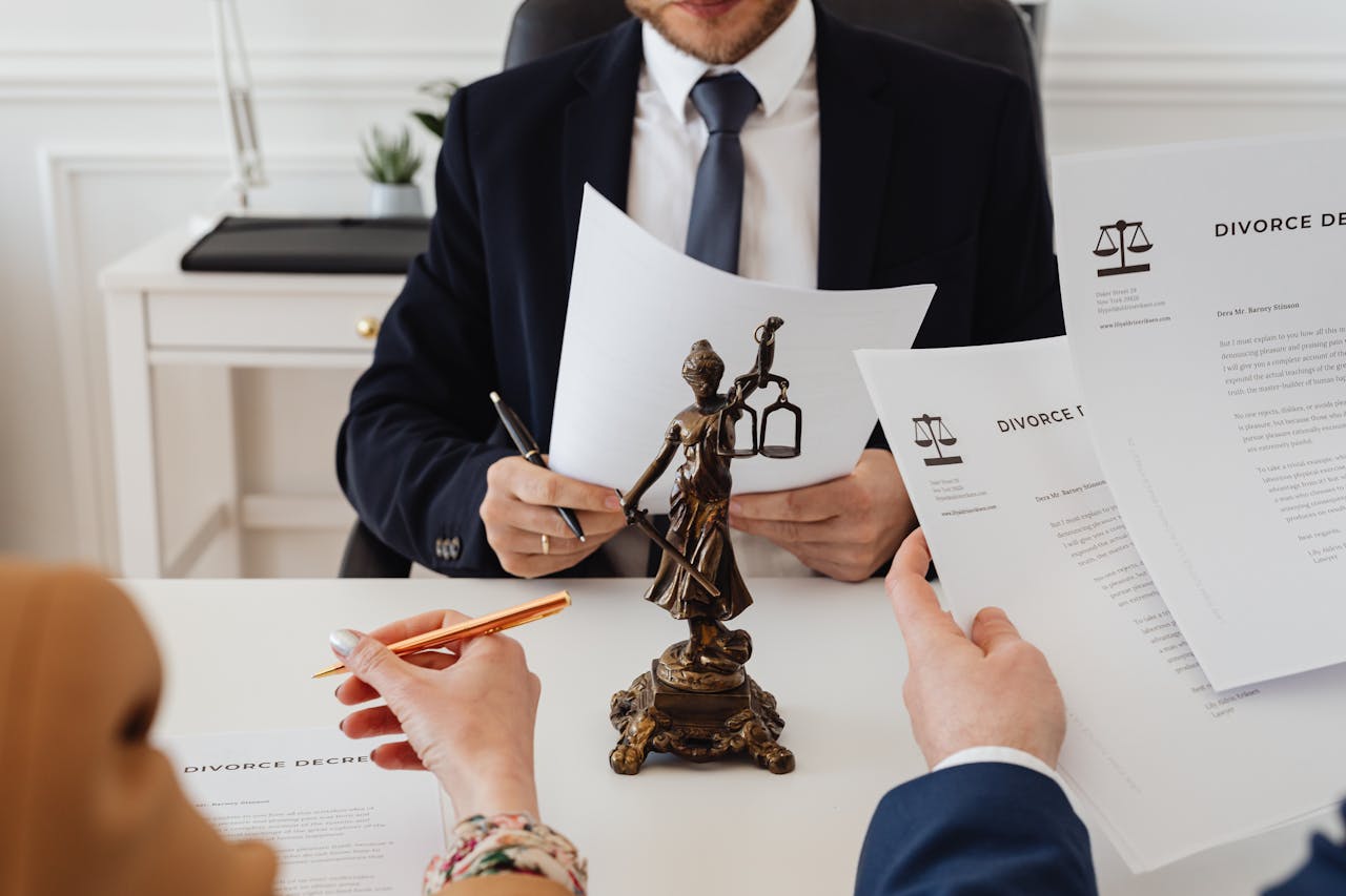About Legal professionals reviewing divorce documents in a law office with a Lady Justice statue.